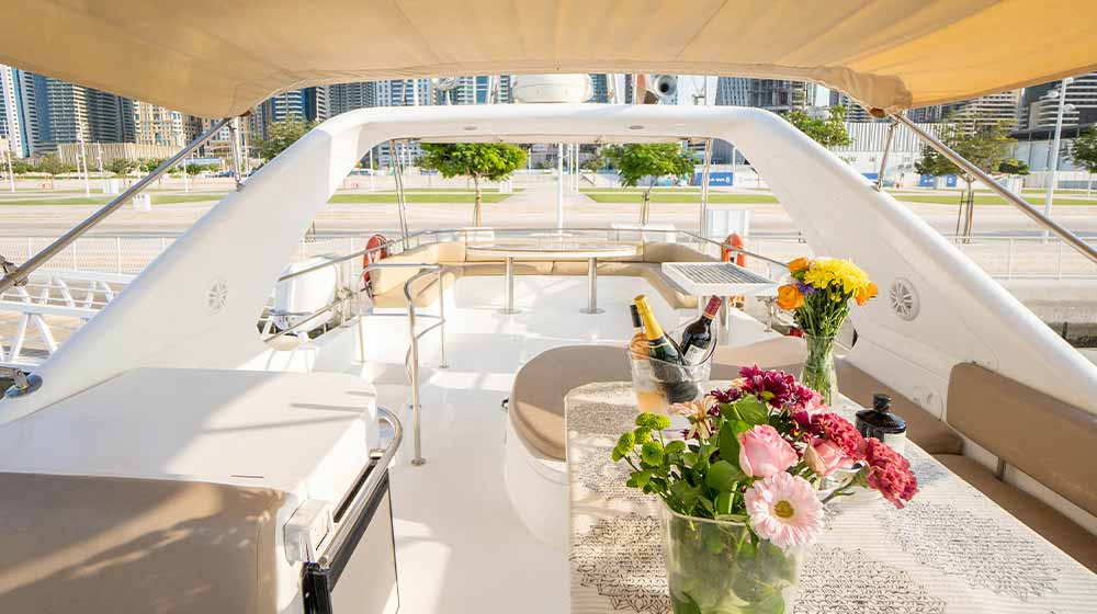 upper deck of yacht with seating, dinette, wine, champagne bottles and bouquet of colorful flowers